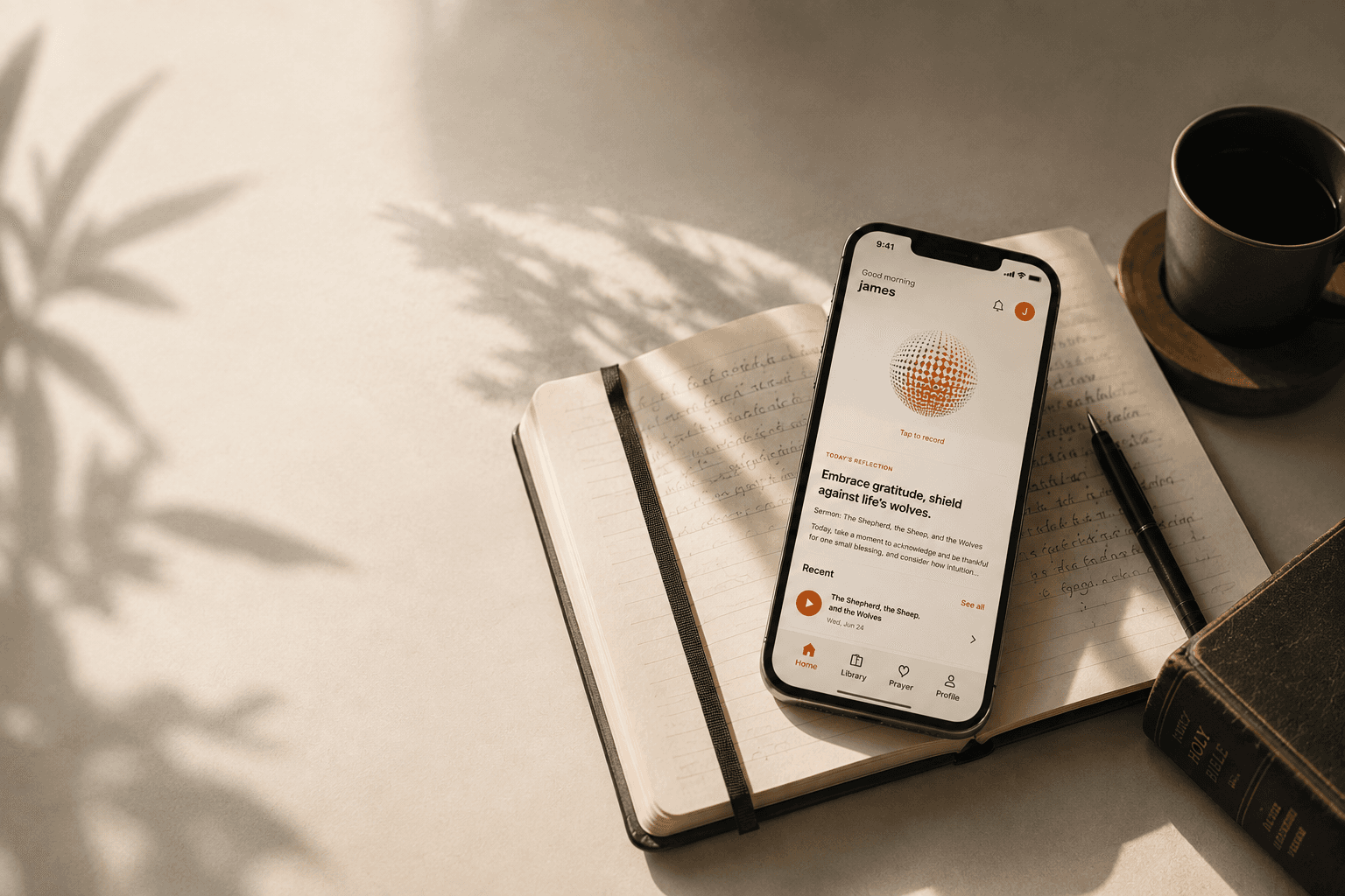 A phone showing the Remnant app resting on an open handwritten journal, beside a Bible and coffee in warm morning light